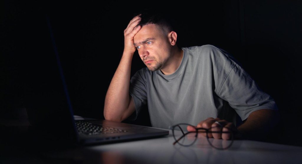 Young man works at the computer at night