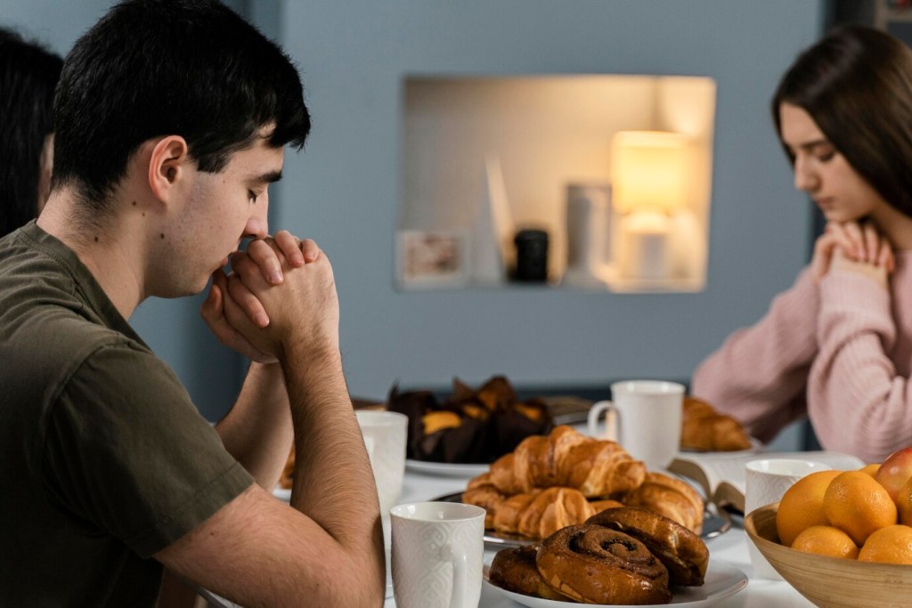 People at home praying before dinner