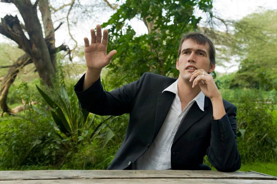 young-man-ordering-garden-restaurant-giving-hand-sign