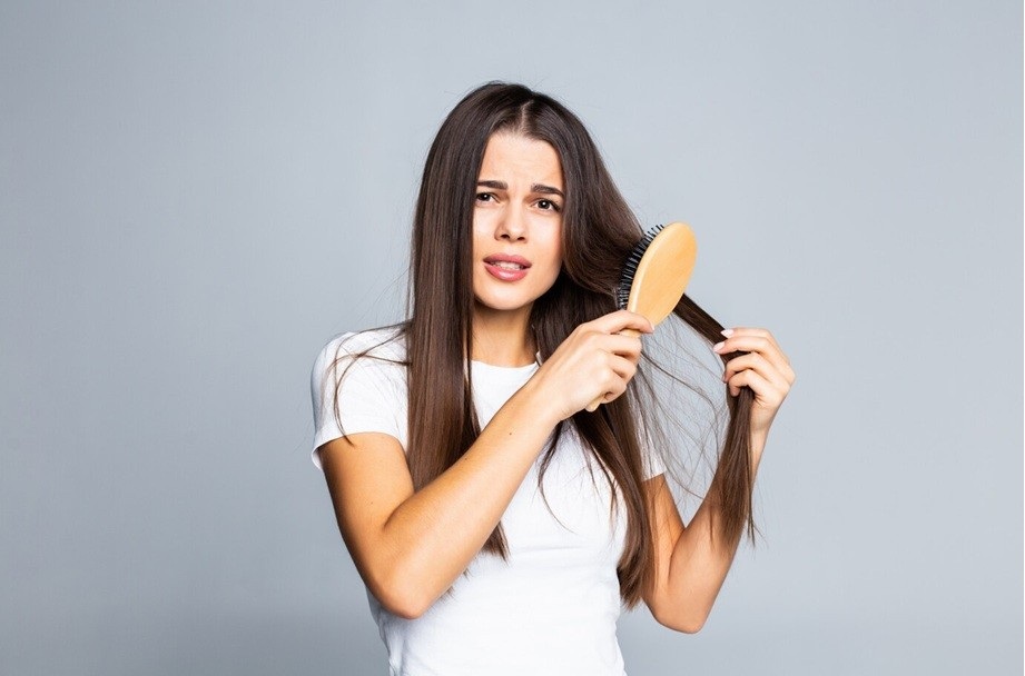 how many strands of hair do you lose a day - Woman combing her hair