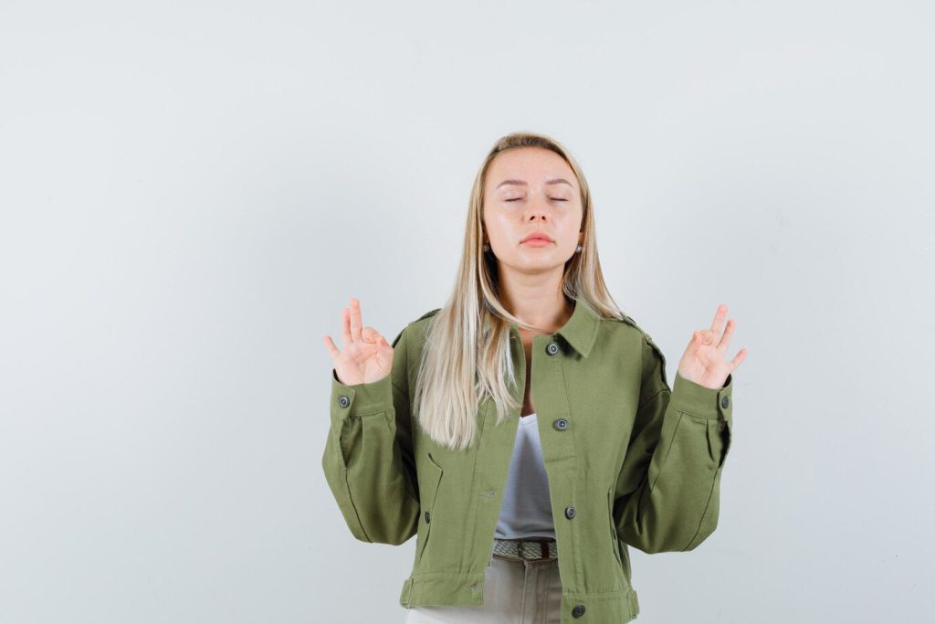 Young lady doing meditation with closed eyes in jacket
