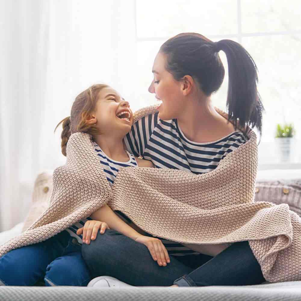 Two people sharing a blanket on a couch, reflecting happiness for stay-at-home moms in NYC.