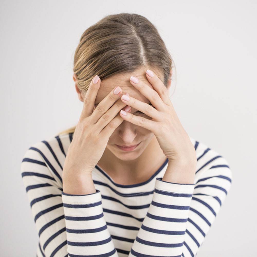 Person in a striped shirt holding their head, reflecting post-trauma stress in NYC.