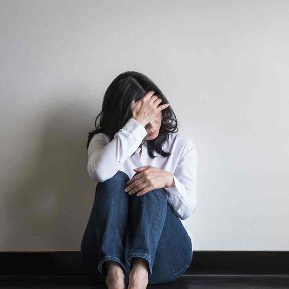 Woman sitting on the floor with a distressed look, discussing panic disorder as a disability in NYC.