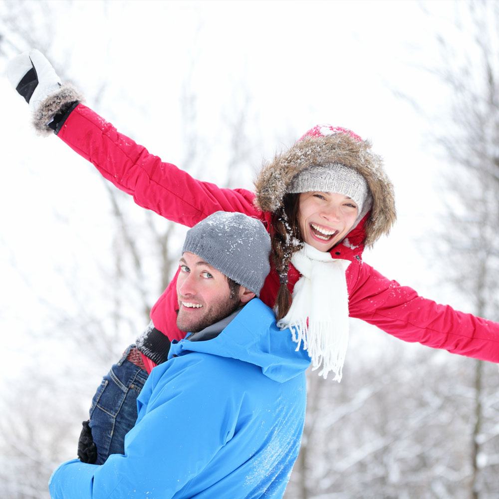 Adult in a blue jacket holding a woman, enjoying snowfall, keeping relationships exciting in NYC.
