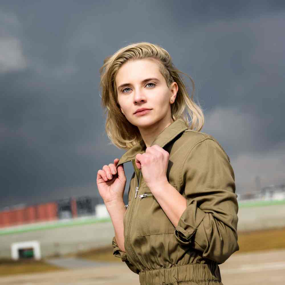Woman in a khaki jacket with stormy skies, reflecting the high price of hyperindependence in NYC.