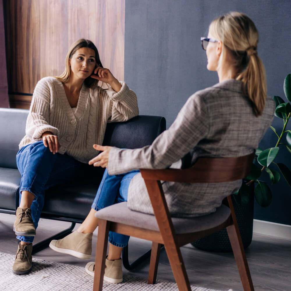 Two people in conversation in a stylish room, exploring the importance of therapy for women in NYC.