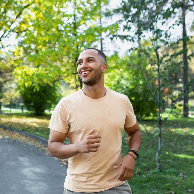 Cheerful and successful hispanic man jogging in the park, man running on a sunny day.