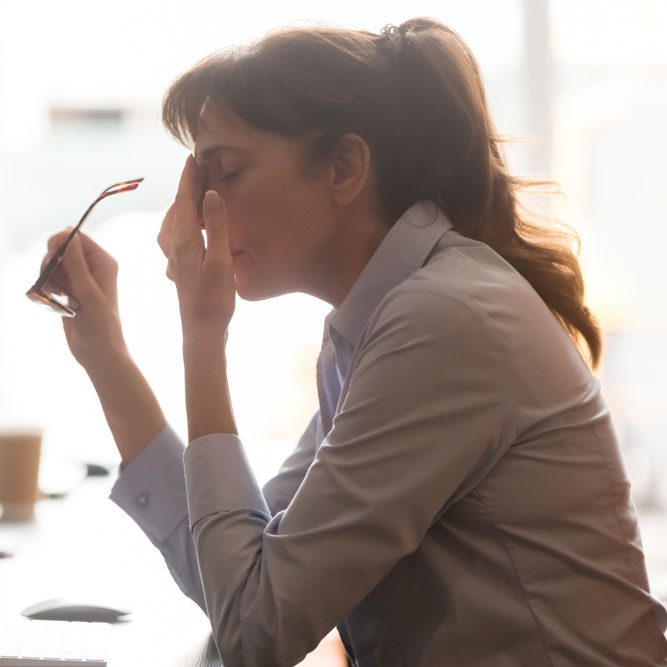 Female worker sit at office desk take off glasses feel unwell having dizziness or blurry vision