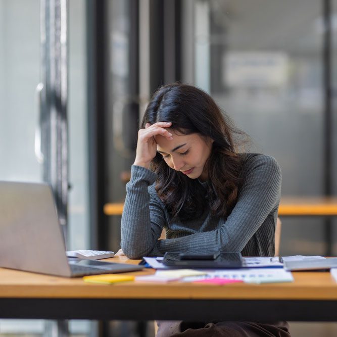 Portrait of tired young business Asian woman work with documents tax laptop computer in office.