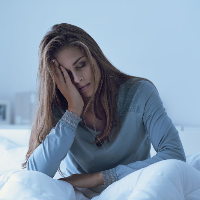 Depressed woman awake in the night, she is touching her forehead and suffering from insomnia