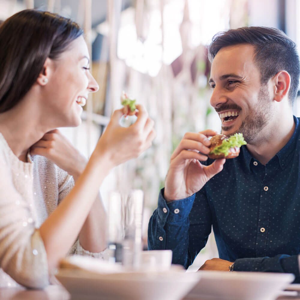 Two people eating sandwiches at a restaurant, exploring tips for dating with anxiety in NYC.
