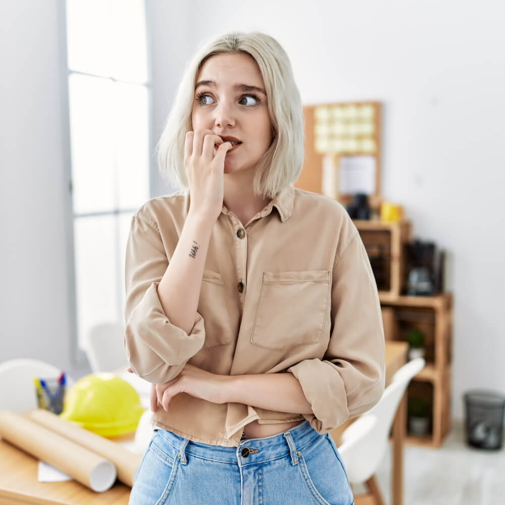 Person in a beige shirt in an office with hardhats, distinguishing anxious vs. nervous in NYC.