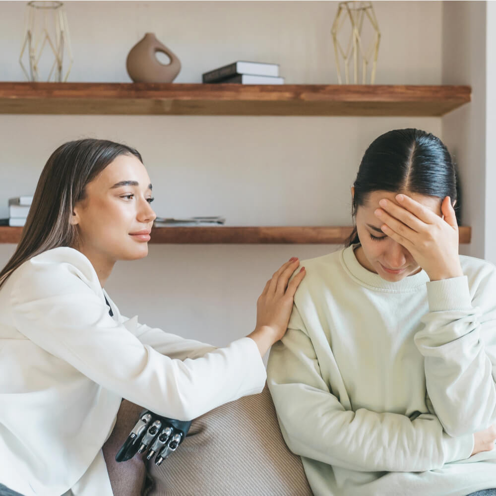 Two people on a couch, one comforting the other, addressing friendship burnout in NYC.