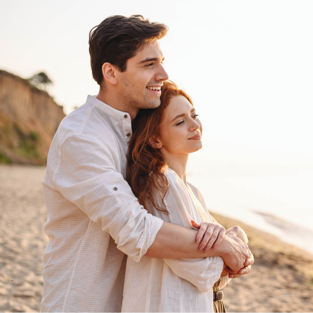 Couple embracing on beach at sunset, stages of dating in NYC.