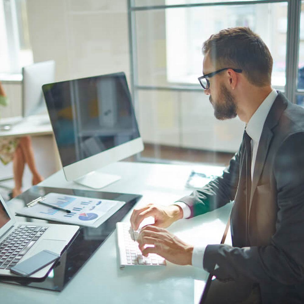 Businessman in a suit typing at a desk, exploring avoidant attachment at work in NYC.