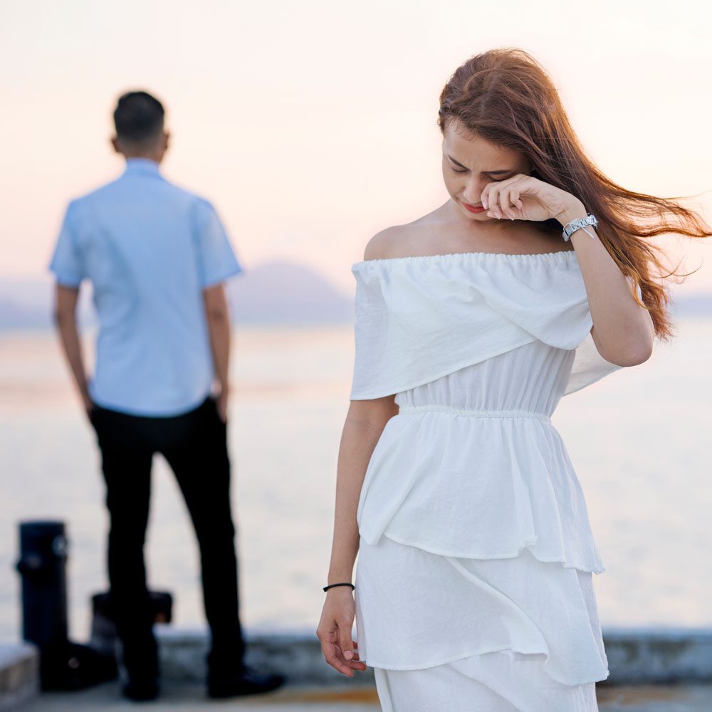 Woman in a white dress facing another person, exploring impostor syndrome in relationships in NYC.