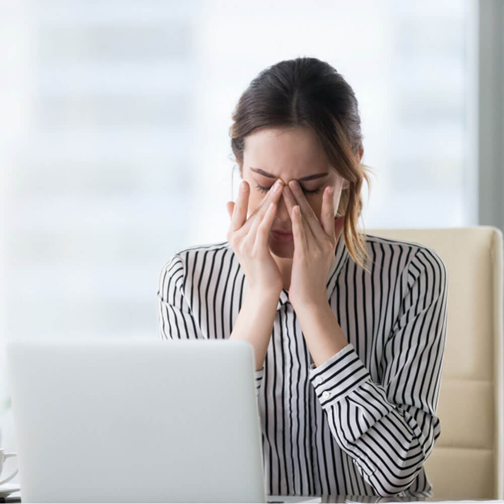 Woman in striped shirt using a laptop at a desk, exploring stress and hormonal imbalance in NYC.