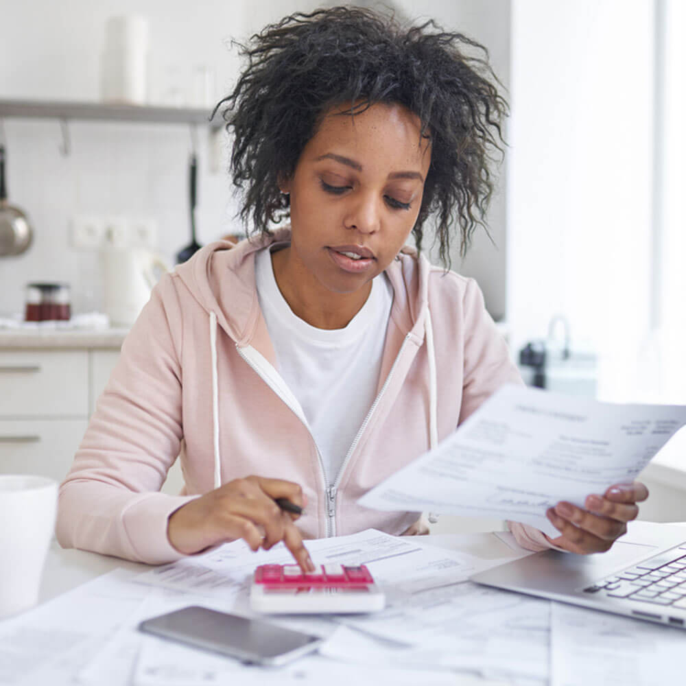 Person with documents and calculator at a desk, linking financial literacy and mental health in NYC.