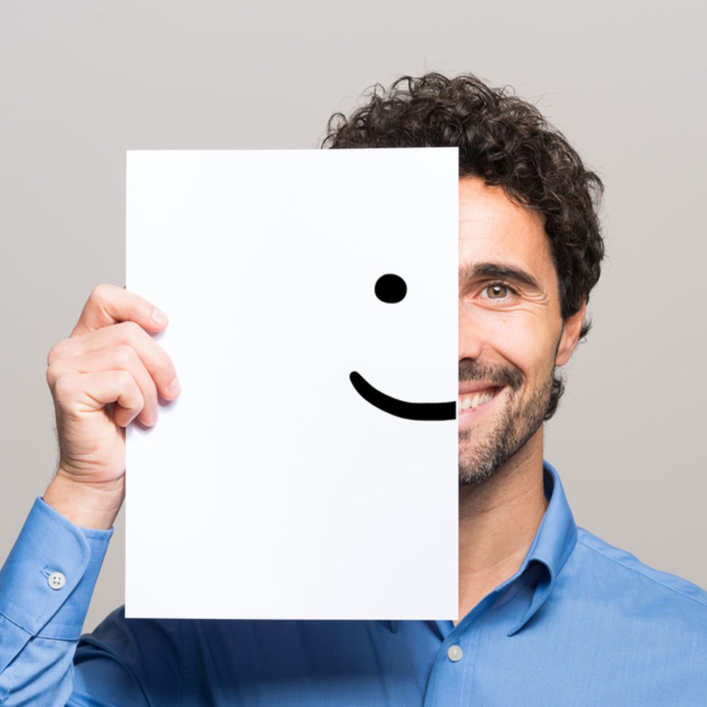 Person in a blue shirt holding a blank white paper, exploring happiness for overachievers in NYC.