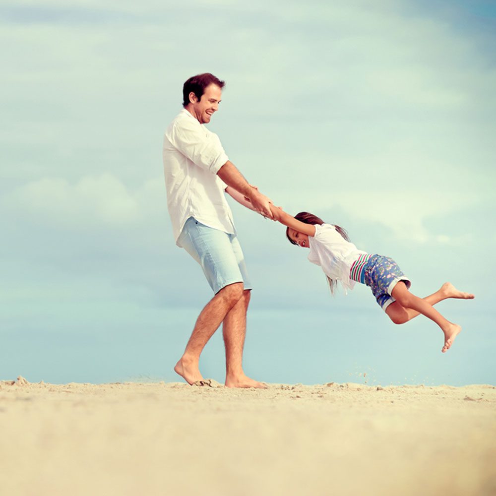 Man and child playing on beach, keys to a happy life in NYC.