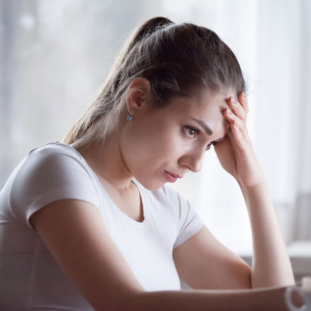 Woman in white tee, hand on head, debunking NYC psychotherapy myths and reality.