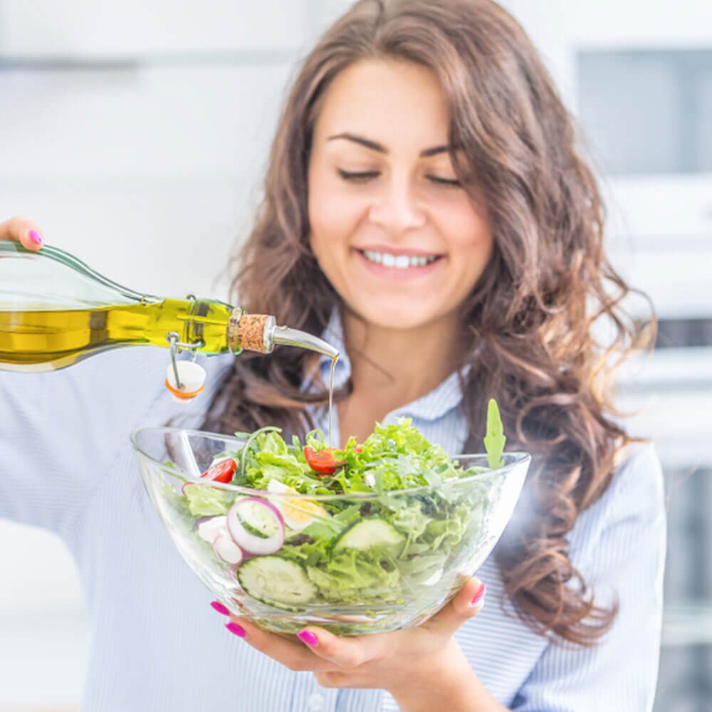 Person pouring olive oil into salad bowl, Mediterranean diet for depression management in NYC.
