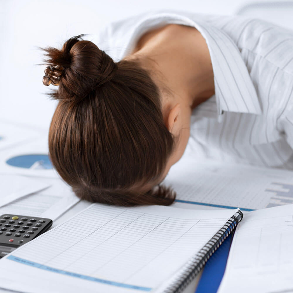 Person with head on desk, affected by silent economic depression in NYC - Uncover Counseling.