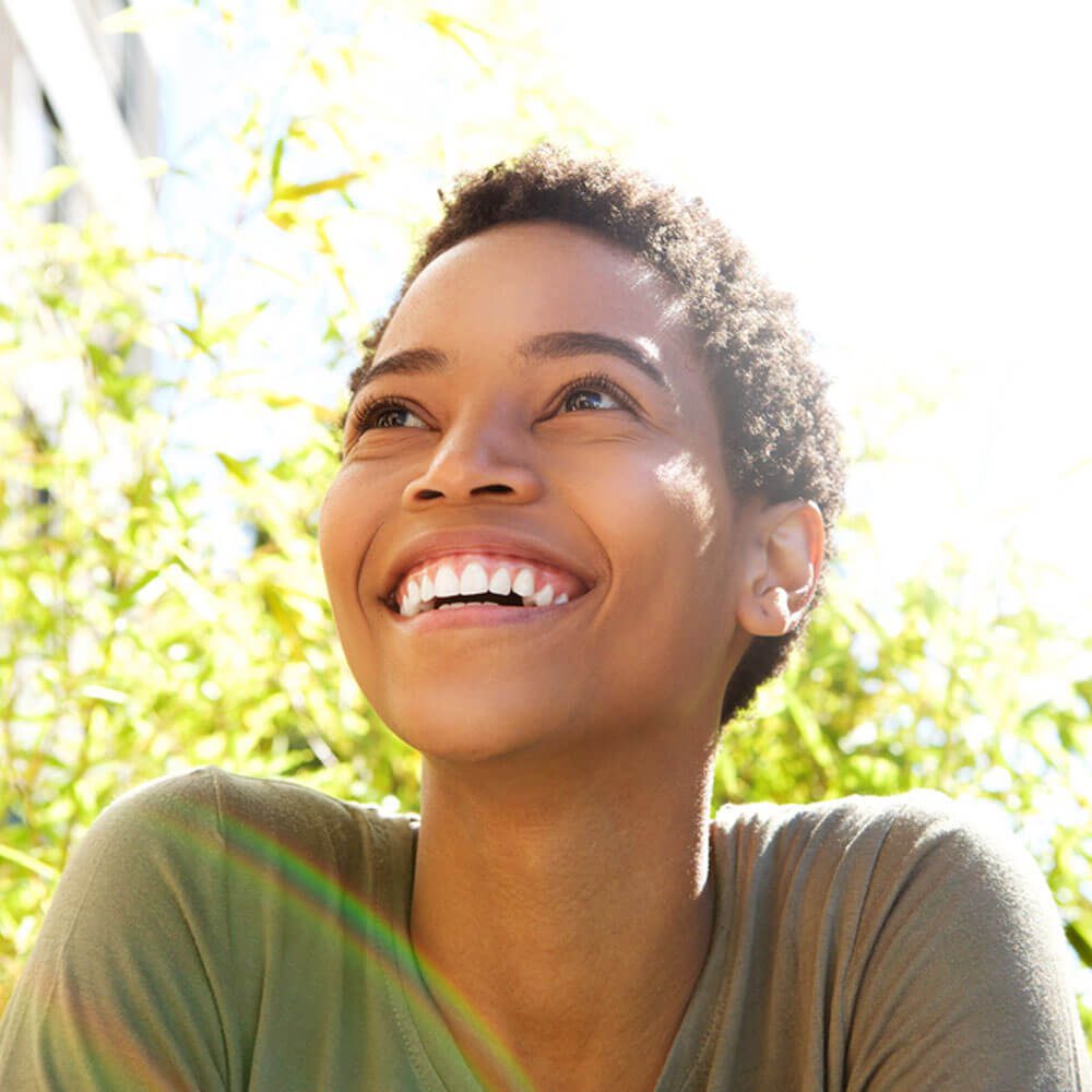Person in a green shirt with sunlit foliage, exploring happiness and its importance in NYC.