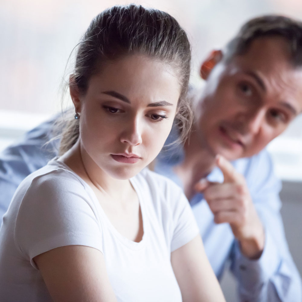 Woman in a white shirt facing away, reflecting on emotional abuse in NYC.
