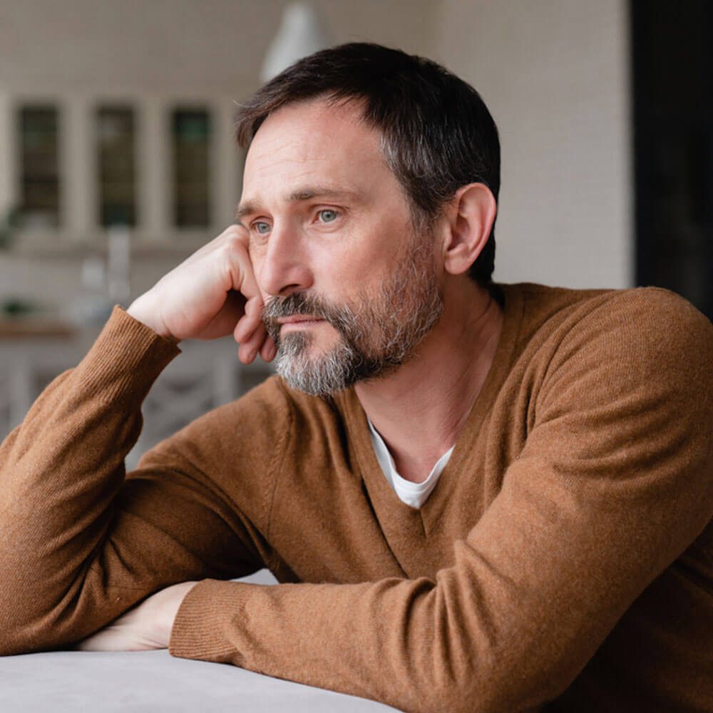 Person resting chin on hand at a table, embracing resilience in NYC - Uncover Counseling.