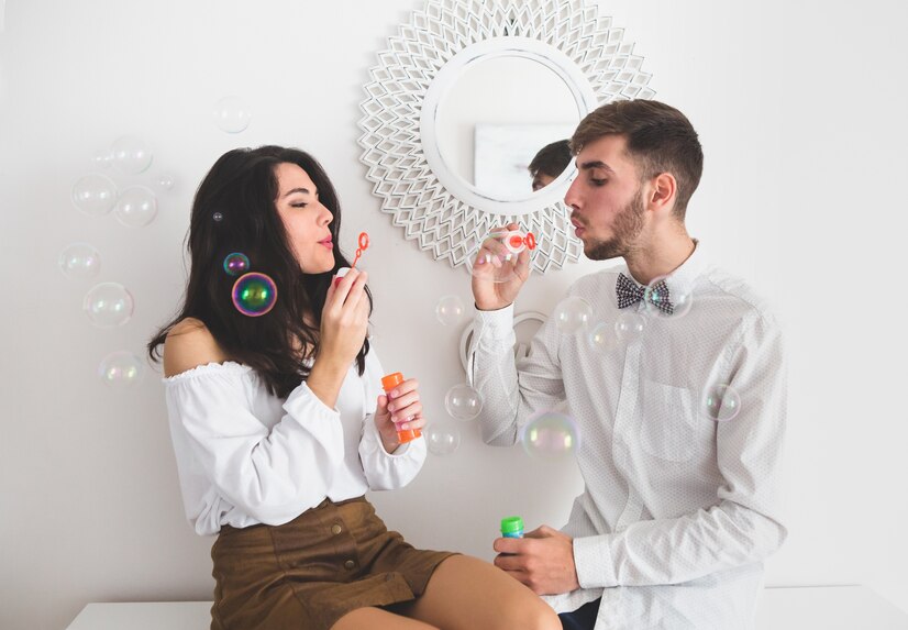 dating in nyc - a couple sitting on the couch blowing soap bubbles