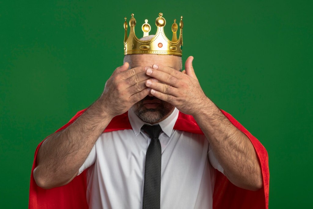 machiavellian traits - a person wearing a red cape and a crown while covering his eyes for surprise