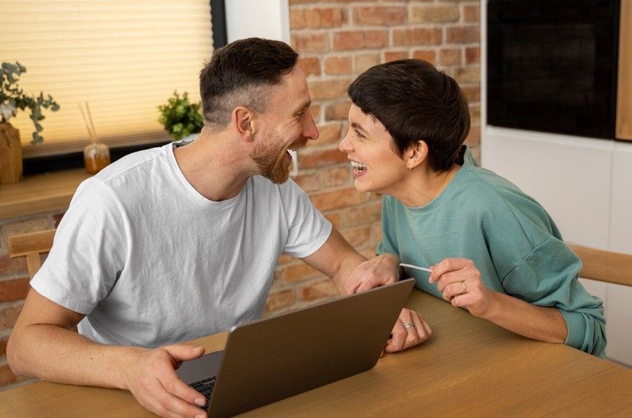 how to communicate in a relationship - two person sitting on a chair, laughing while doing work