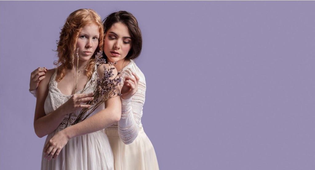 Two women in elegant dresses pose together.